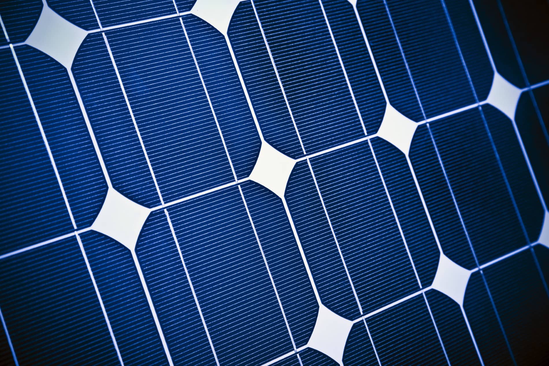 Close-up view of blue solar panel cells with fine white grid lines and geometric patterns, highlighting the texture of photovoltaic cells used to capture sunlight for electricity generation—ideal for those seeking a solar rebate.