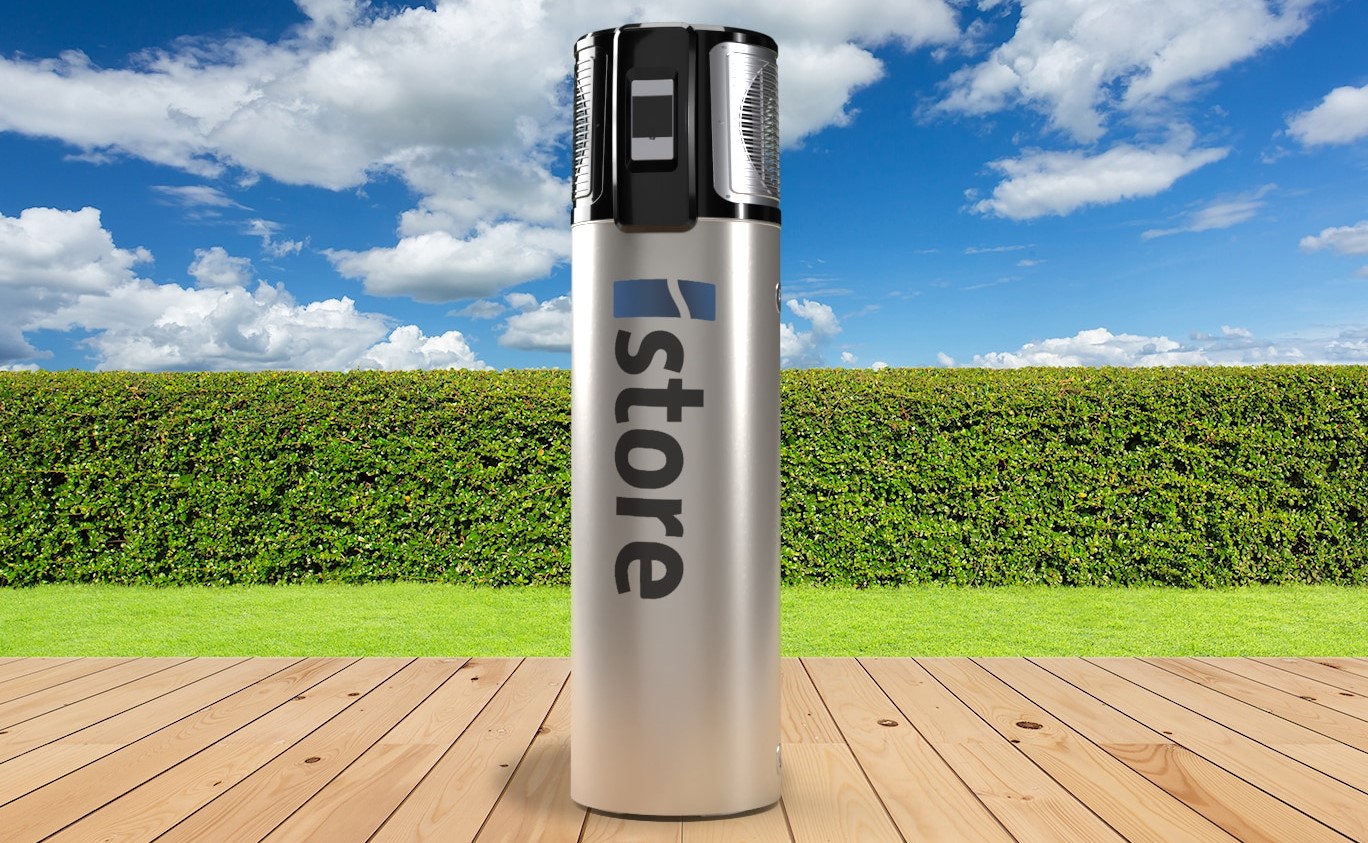 A large metallic battery with the word “store” printed on it stands on a wooden decking, highlighting battery rebate options, with a green hedge and a blue sky with clouds in the background.