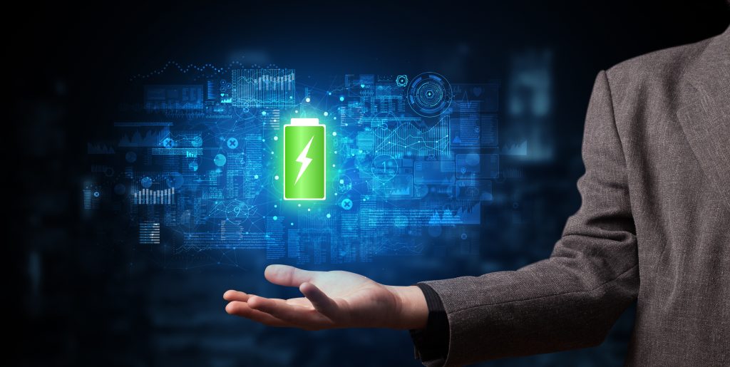 A person in a suit holds out their hand with a glowing green battery rebate icon floating above it, surrounded by digital technology symbols and a dark, futuristic background.