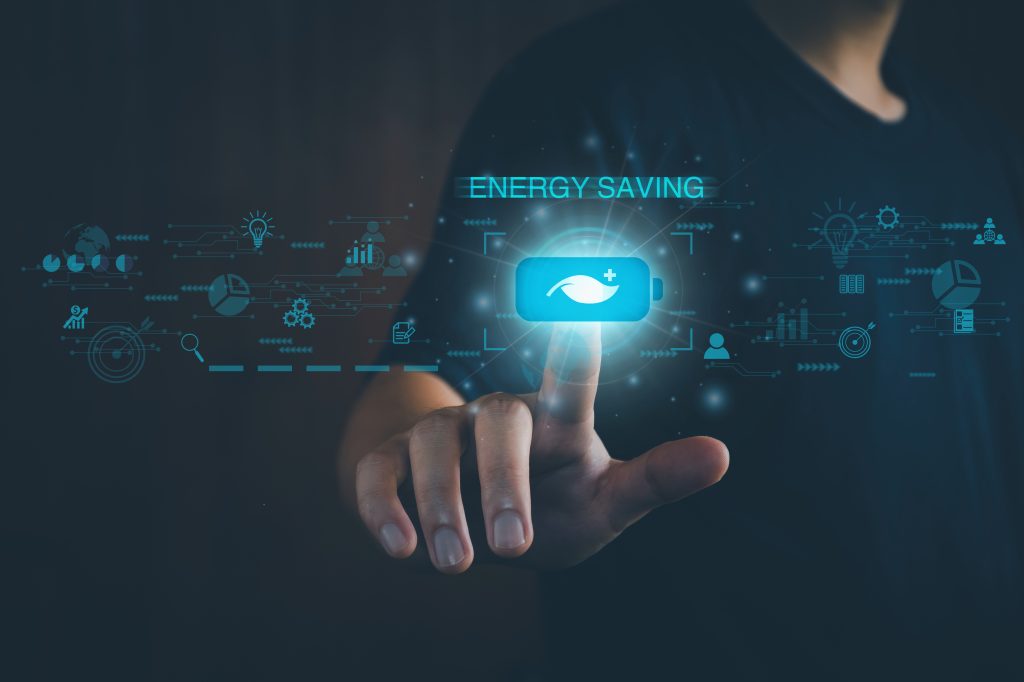 A person touches a virtual button labelled "Energy Saving" with a battery icon, surrounded by digital energy and technology symbols—hinting at appliance rebate opportunities and government grants on a dark background.