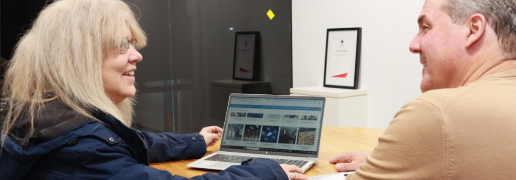 Two people sitting at a desk discussing energy efficiency information on a laptop, related to REPS in South Australia and upcoming changes in 2026